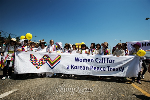  24일 오후 경기도 파주 통일대교 남단에서 위민크로스DMZ 행사를 참가하기 위해 북한에서 육로로 방한한 세계여성운동가들과 시민들이 '평화통일 기원 조각보'를 함께들고 행진을 준비하고 있다. 