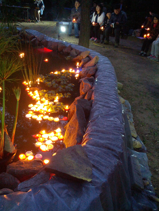 성거산성지 '성모의 밤' 행사에 참례한 신자들이 연못 위에 띄운 촛불들이 바람결에 따라 옹기종기 모여 있다. 