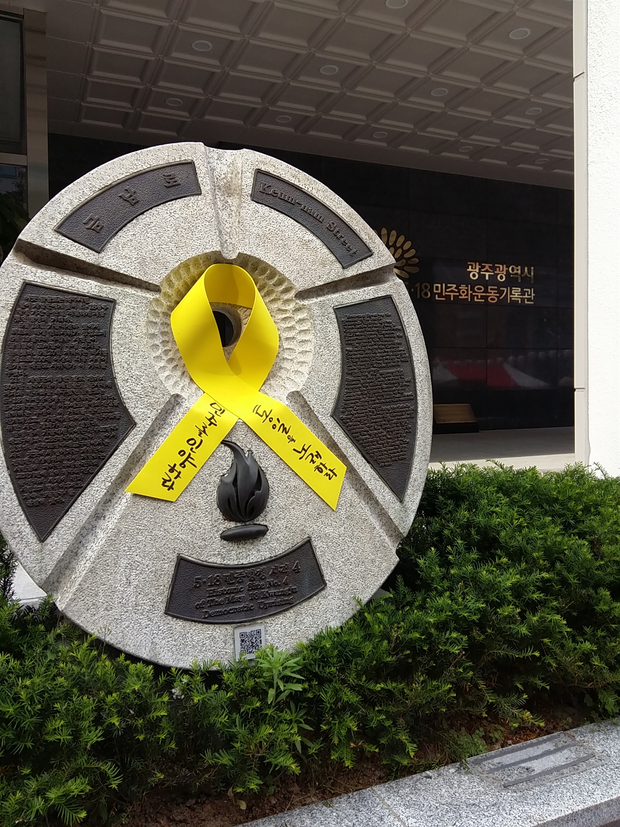 5.18 민주화운동 기록관 앞 기념석에 ‘민주를 인양하라, 통일을 인양하라’고 쓴 노란 리본이 달려 있다. 
