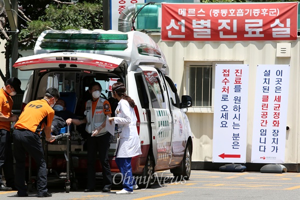  지난 4일 오전 메르스(중동호흡기증후군) 선별진료실이 설치된 서울 중구 국립중앙의료원 응급실앞에서 마스크를 착용한 119대원과 의료진이 구급차에서 환자를 내리고 있다. <자료사진>