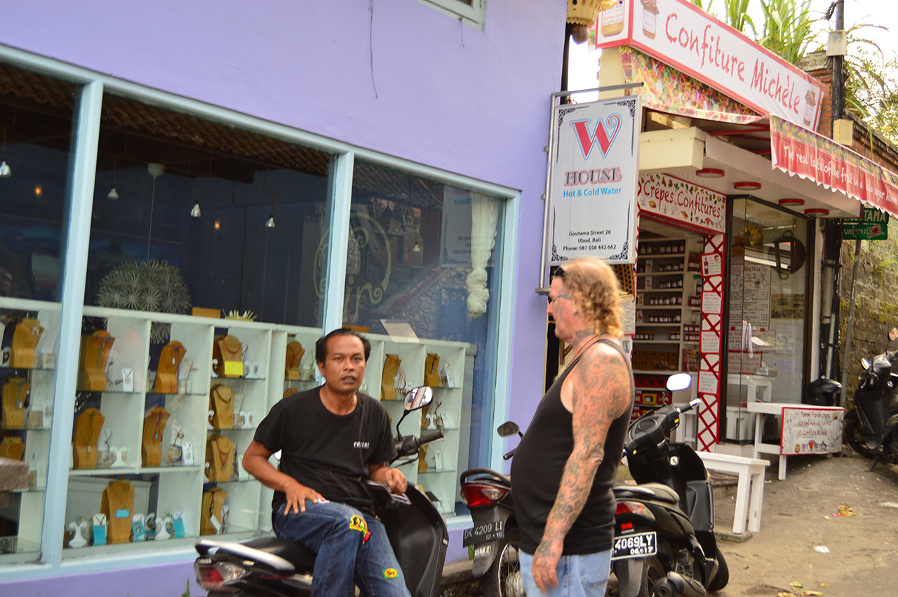 온 몸에 문신을 한 여행자가 유명한 유기농 잼 가게 앞에서 발리인과 이야기를 나누고 있다.