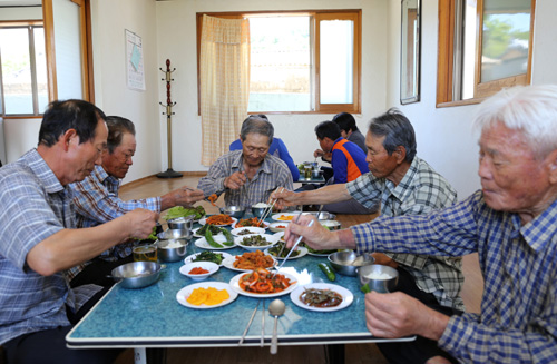 지난 5월 27일 장자마을 주민들이 마을회관에 모여서 점심 식사를 하고 있다. 들녘에서 일하다 들어온 이재석 할아버지가 가운데에 앉아 있다.