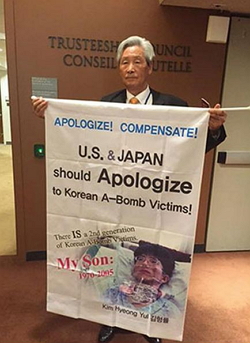 원폭피해 참상을 알리기 위해 아들의 사진이 있는 피켓을 들고 있는 김봉대 선생 