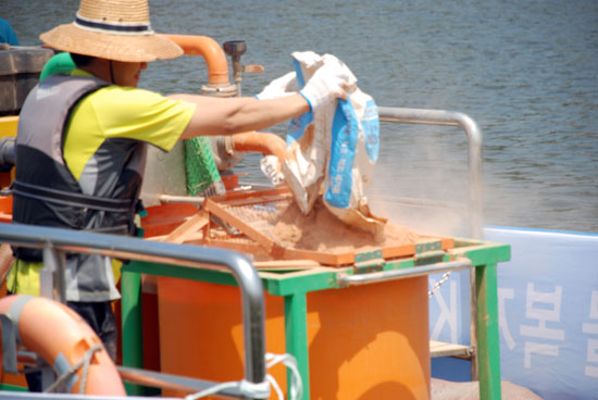 수자원공사가 공주보에서 사용하는 ‘웅진호’ 바지선에서 직원이 녹조 제거를 위한 ‘워터 클린’을 장비에 투입하고 있다.