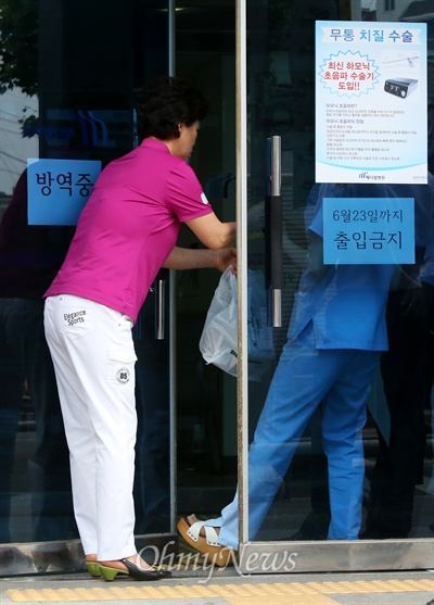 요양병동에 입원중이 환자 가족이 출입문앞에서 환자에게 전달할 물품을 직원에게 전하고 있다.