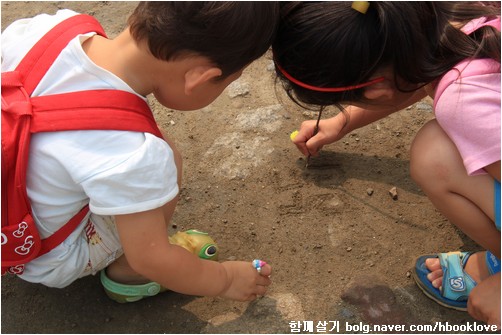 흙바닥에 글씨를 쓰며 노는 아이들.
