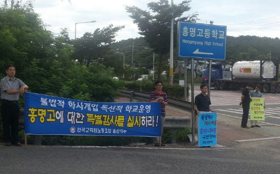  2013년 7월 23일 울산 울주군 청량면 온산로에 있는 홍명고등학교 앞에서 이사장에 복귀한 이사장이 학사개입 등을 하고 있다며 교육청의 특별 감사를 촉구하는 시위를 벌이고 있다. 결국 감사를 벌인 울산교육청이 이사장의 배임 혐의를 확인했고, 학교법인 이사회는 6월 22일 이 이사장을 해임했다. 