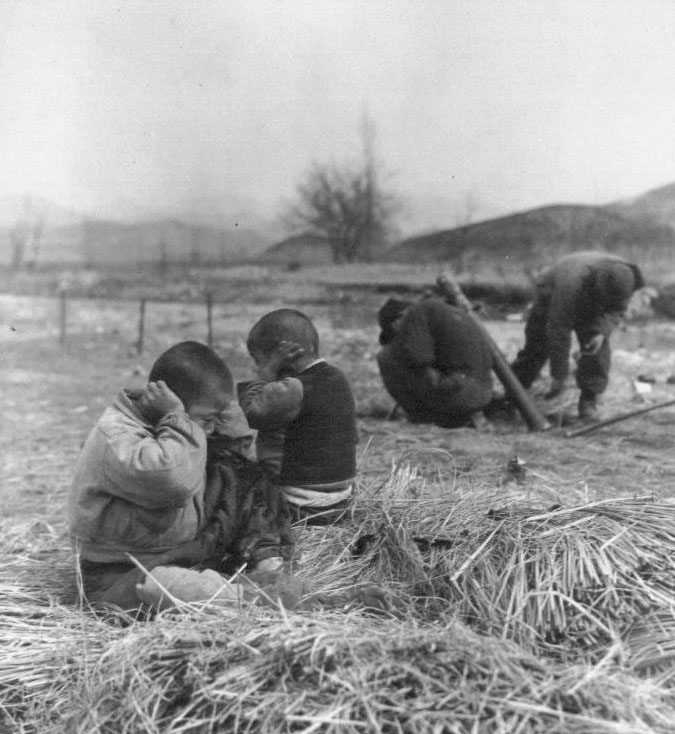  유엔군들이 박격포를 쏘는 한강 부근에서 두 소년이 귀를 막고 있다(1951. 3. 4.)