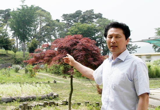 숲이 우거진 교정을 설명하는 정선만 교장
