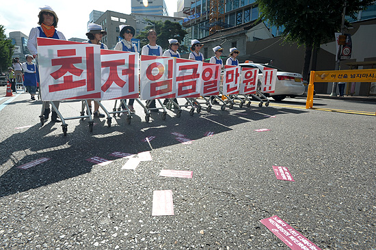 27일 오후 서울역 광장에서 개최된  '최저임금 1만원 쟁취 노동시장 구조개악 저지 전국노동자대회'에 참가한 홈플러스 노동자들이 '최저임금 1만원'을 요구하며 행진하고 있다.