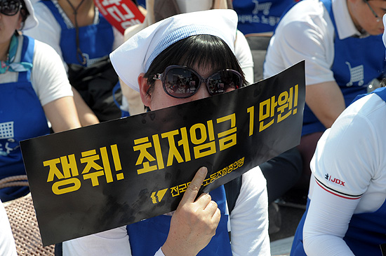 27일 오후 서울역 광장에서 민주노총이 주최한 '최저임금 1만원 쟁취 노동시장 구조개악 저지 전국노동자대회'에서 한 참가자가 '최저임금 1만원 쟁취' 피켓을 들어 보이고 있다.