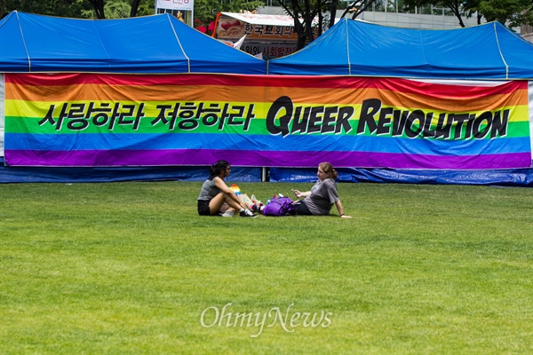 28일 서울광장에서 열린 퀴어문화축제 참가자들이 무지개 현수막 앞에 앉아 휴식을 하고 있다. 