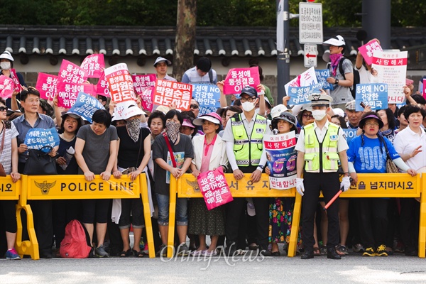 28일 오후 서울광장에서 열린 퀴어문화축제 반대집회 참가자들이 피켓을 들고 서 있다.