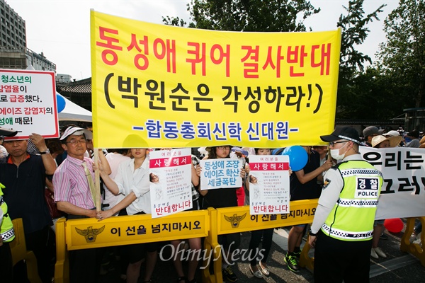 지난해 6월 28일 열린 퀴어문화축제의 반대집회 참가자들이 피켓을 들고 서 있다. 