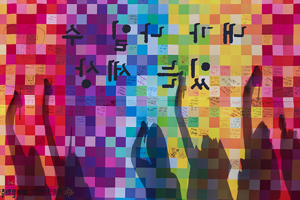 28일 오전 서울광장에서 열린 제16회 ‘퀴어문화축제’를 찾은 시민들이 포토월에 응원 문구를 적고 있다.
