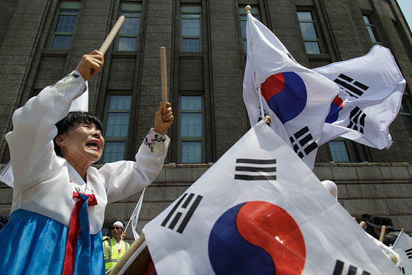 28일 오후 서울광장에서 열린 ‘퀴어문화축제’에 반대 하는 기독교 신자들이 태극기가 휘날리는 가운데 북을 치고 있다.