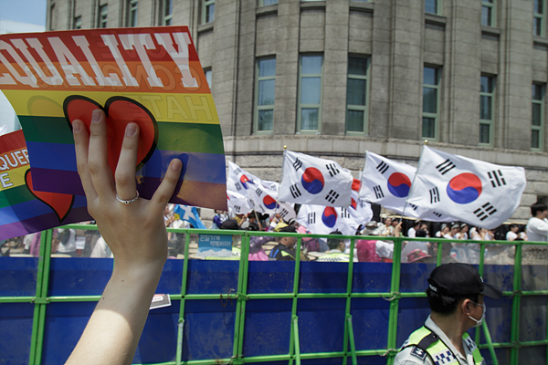 28일 오후 서울광장에서 열린 ‘퀴어문화축제’에서 한 참가자가 반대자들을 향해 행사 포스터를 흔들어 보이고 있다.