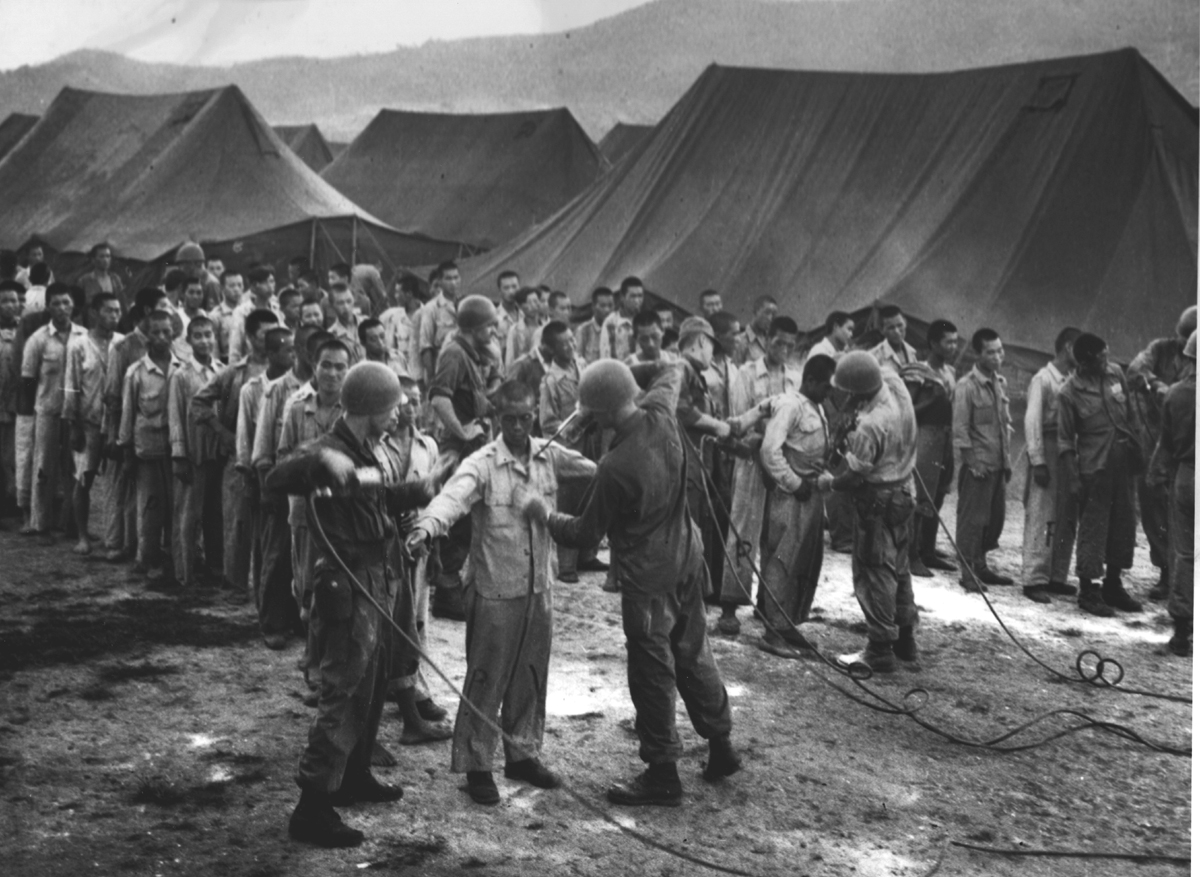 유엔군 감시병들이 거제도포로수용소 포로들에게 DDT를 살포하고 있다(1952. 8.).