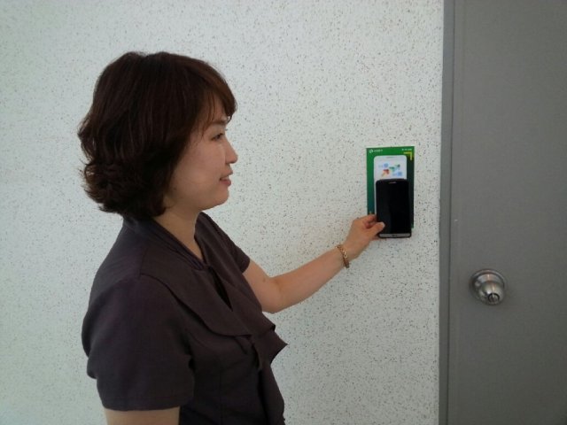서대문구 주민이 아파트 벽에 설치된 NFC스티커에 스마트폰을 대고 있다.