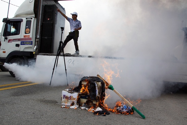 집회 주최 측에서 탄저균 불법 반입ㆍ실험에 항의하는 뜻으로 택배상자를 불태우고 있다.