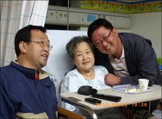 병원에 입원한 어머니와 단란한 한 때를 보내고 있는 김호진씨 가족. 사진 왼쪽이 김호진씨

