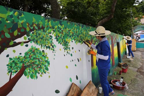 지난 2일 자원봉사자들이 월곡마을 담장에 벽화를 그리고 있다. 