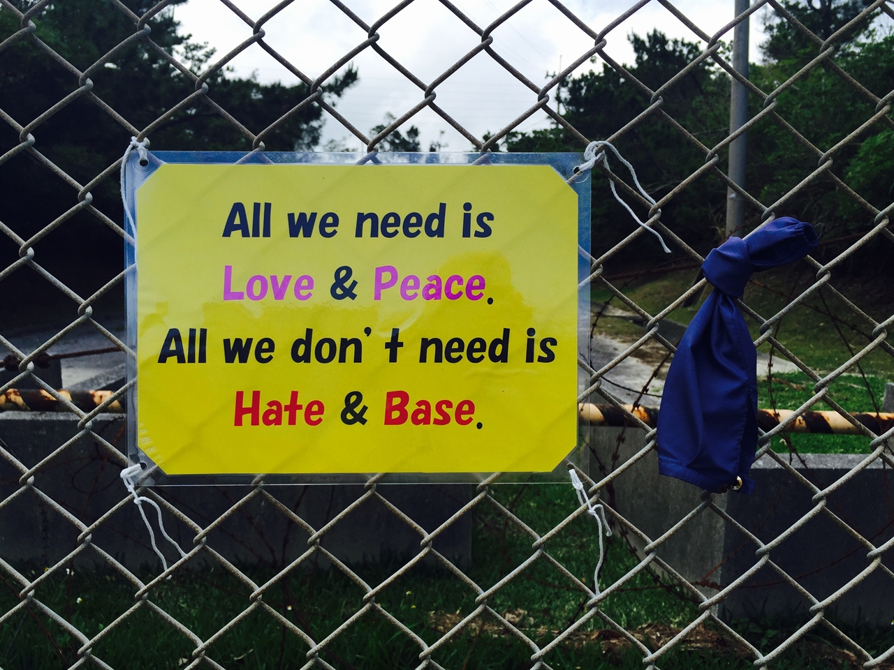 헤노코 기지 건설이 진행되고 있는 캠프 슈와브 앞 철조망에 붙은 문구. "우리에게 필요한 것은 사랑과 평화. 우리에게 필요없는 것은 증오와 기지"