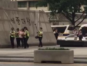 지난 27일 오후 7시께 미 대사관 앞 시위를 지켜보고 있던 여성이 연행되고 있다. 