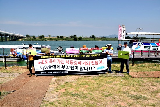 '식수원 낙동강 지키기 시민행동' 소속 회원과 활동가들이 달성군의 유람선과 쾌속선이 정박해 있는 선착장 앞에서 기자회견을 열고 있다