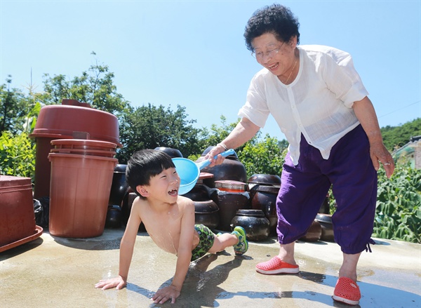  5일 함양 서상면 대로마을에서 한영숙(82) 할머니가 손자 등에다 물을 부어주고 있다.