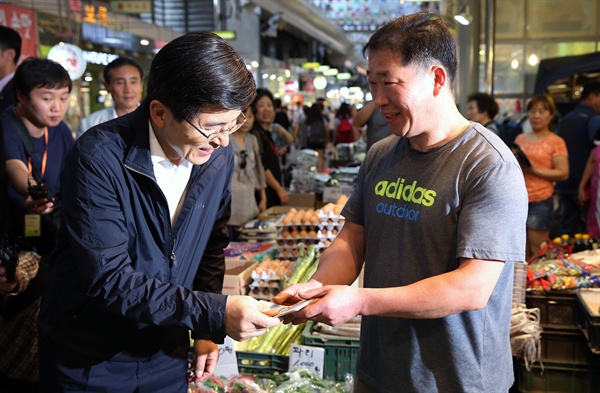 황교안 국무총리가 지난 7월 9일 오후 서울 강동구 암사동 암사종합시장을 방문해 채소가게에서 야채를 구매한뒤 온누리상품권을 지불하고 있다.