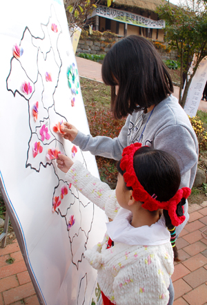 어린이들이 한반도 지도에 종이로 만든 나라꽃 무궁화를 붙이고 있다. 자료사진