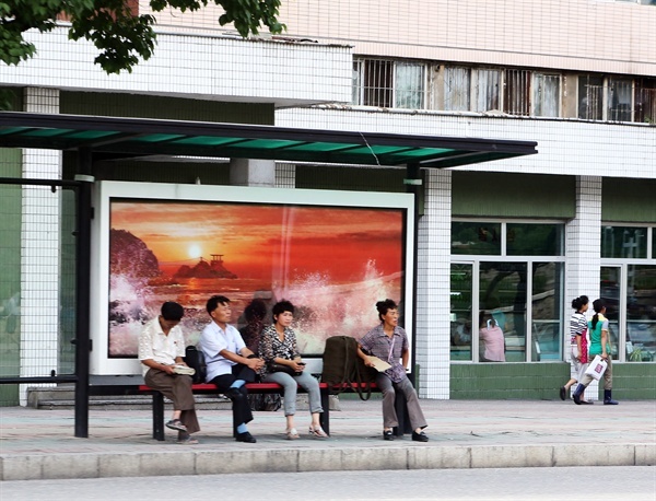 버스정류장에 앉아 있는 평양 시민들.