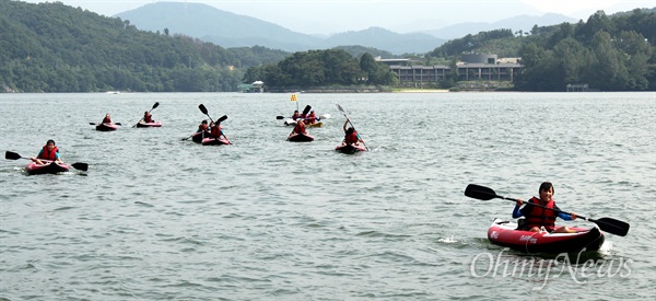 강 건너편에서 물 적응 훈련을 한 후 고무 카누를 저어서 나루터로 돌아오는 학생들. 