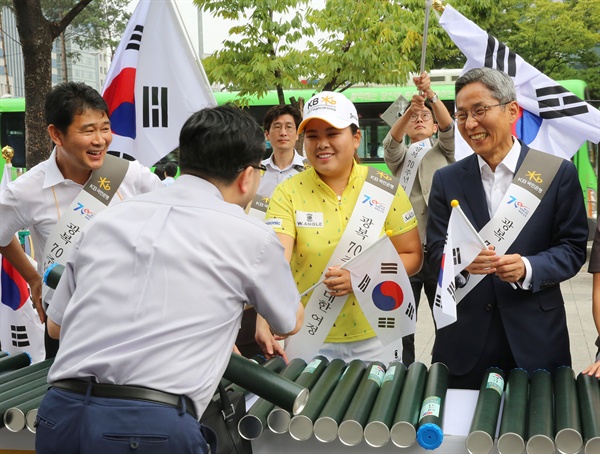 KB국민은행 윤종규 은행장과 박인비 선수가 고객들에게 태극기를 나눠주는 모습