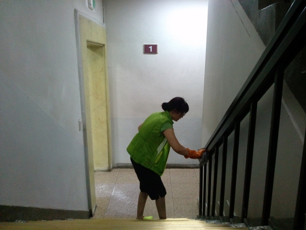 중앙도서관을 담당하는 청소노동자가 손걸레로 계단 난간을 닦고 있다. 그녀는 하루 두 번 출·퇴근한다.