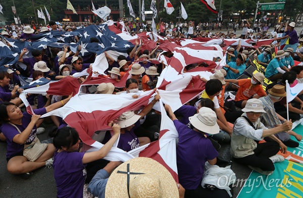 15일 오후 서울 대학로에서 열린 8·15 반전평화 범국민대회 참가자들이 종각사거리까지 행진 후 정리 집회를 하며 미국 성조기와 일본 욱일승천기를 합친 대형 깃발을 찢는 퍼포먼스를 하고 있다.