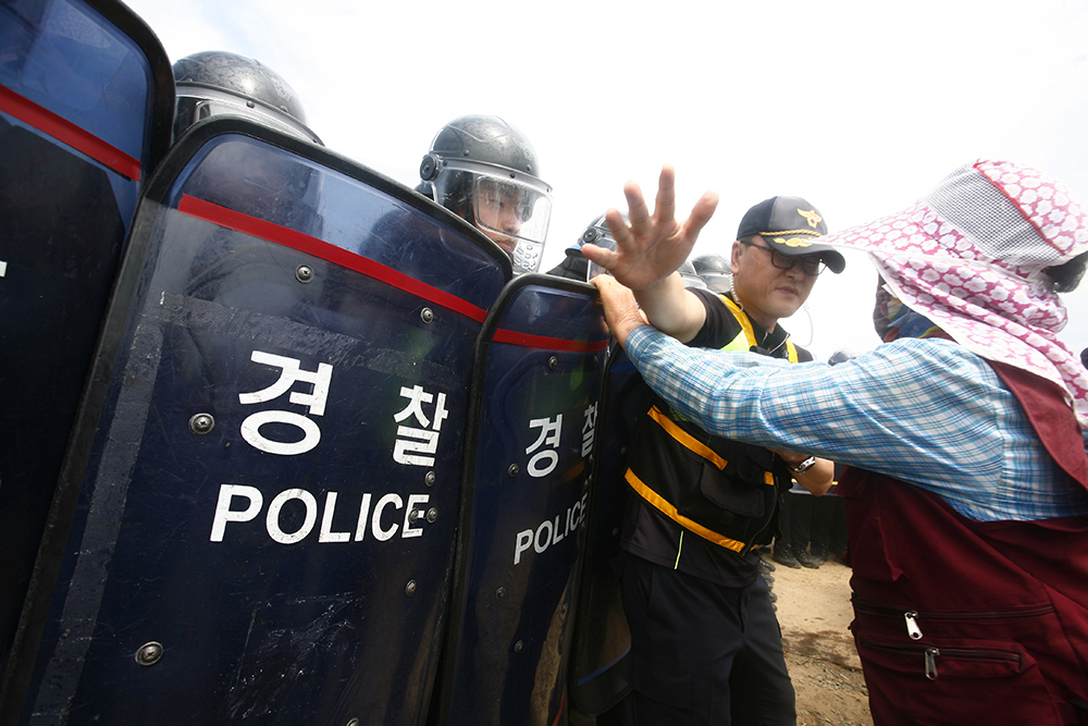 18일(화) 지역주민들과 한전 직원들은 군산시 산북동 88번 송전철탑 건설 현장에서 충돌하자 경찰 병력이 출동했다. 이에 한 주민이 경찰에 항의하다 제지를 받고 있다. 