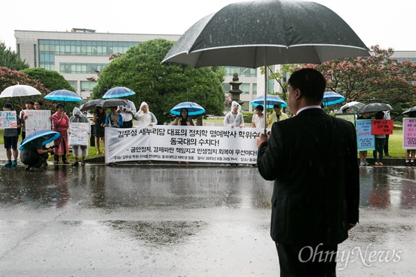 새누리당  김무성 대표가 정치학 명예 박사를 수여하기로 한  20일 오후 서울 중구 동국대학교에서 김  대표의 학위 수여를 반대하는 학생들이 피켓을 들고 철회를 촉구하자 한 교직원이 이 모습을 지켜보고 있다. 