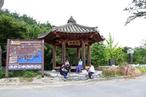 양산원의 집 터에 세워진 남도 이순신길 조선수군 재건로 안내판. 그 옆에는 복원된 오매정에서 마을 주민들이 쉬고 있다. 양산원의 집은 정유재란 당시 조선수군 재건에 나선 이순신이 군량미를 구하고 묵었던 곳이다.