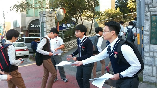유효준군 등 충암고등학교 법·사회 동아리 소속 학생 3명이 2015년 10월 5일 오전 서울 은평구 응암동 충암중·고등학교 정문에서 이 학교 급식 비리를 다룬 기사 복사본을 친구와 후배들에게 나눠주고 있다. 