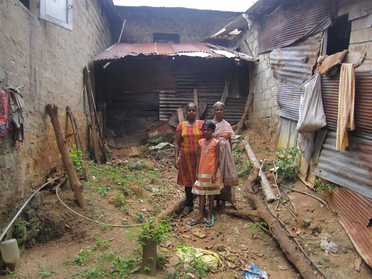 찬드라(위에서 오른쪽)과 시어머니 그리고 당시 두살배기 였던 막내딸이 테러조사국에 의해 부서진 집 앞에 서있다. 