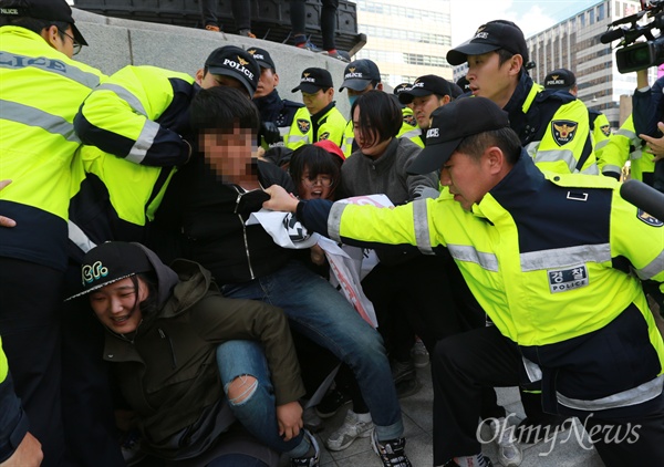 12일 오후 서울 종로구 광화문 이순신 동상 위에서 대학생 10여 명이 올라가 한국사 역사교과서 국정화 강행 처리를 규탄하는 기습시위를 벌이자, 출동한 경찰이 학생의 멱살을 붙잡고 끌어내고 있다.