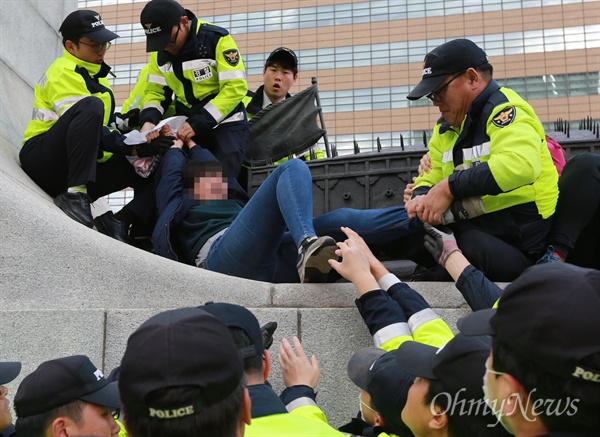 남자 경찰에 사지가 붙잡힌 여학생 12일 오후 서울 종로구 광화문 이순신 동상 위에서 대학생 10여 명이 올라가 한국사 역사교과서 국정화 강행 처리를 규탄하는 기습시위를 벌이자, 남자 경찰들이 여학생의 사지를 붙잡고 끌어내고 있다.