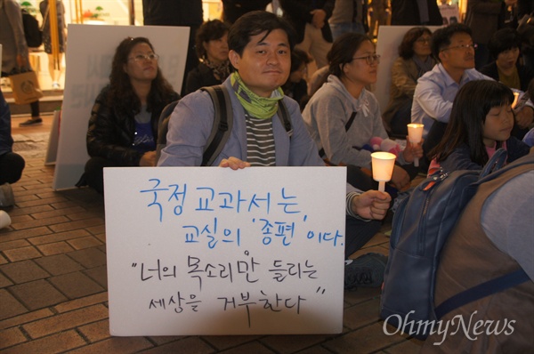 지난 16일 대구시 중구 동성로 한일극장 앞에서 열린 한국사 교과서 국정화 반대 촛불문화제에 참석한 한 시민이 피켓과 촛불을 들고 않아 있다.