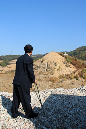 공사 현장에 남아 있는 묘지를 바라다보고 있는 '혈동리 골프장 건설 반대 주민대책위' 김남철 위원장.