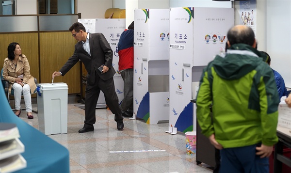 하반기 재보궐 선거가 치러진 28일 오전, 부산 부산진구 연지동 3투표소인 연지동 주민센터에서 한 유권자가 기표한 투표지를 투표함에 넣고 있다.