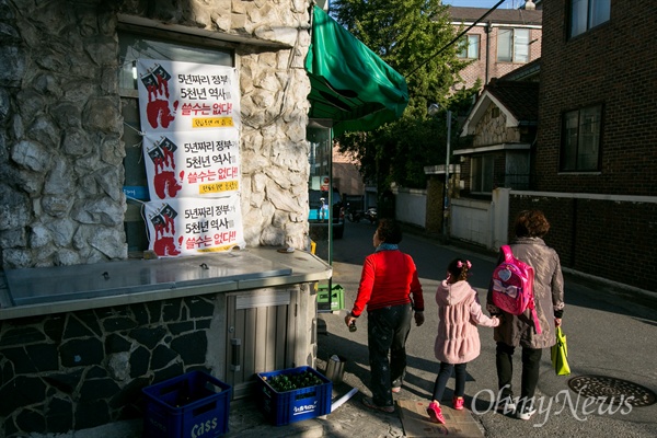 28일 오후 서울 용산구에 9년 째 '동네슈퍼'를 운영하는 이승극씨가 가게 앞에 한국사 국정화교과서 반대 현수막을 내 걸자 지나가던 주민들이 살펴보고 있다. 