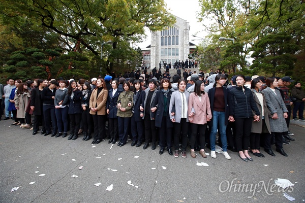  박근혜 대통령 방문에 항의하는 이화여대생들이 대강당으로 접근하는 것을 막기 위해 남녀 사복경찰들이 대강당으로 올라가는 계단앞을 겹겹이 에워싸고 있다.