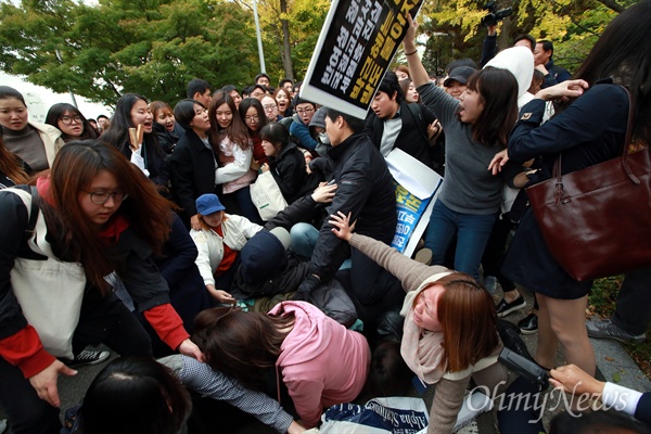박 대통령이 29일 오후 전국여성대회 축사를 위해 방문한 가운데, 같은 시각 밖에서는 이대생과 경찰이 대치 중이었다. 충돌이 벌어져 일부 학생들이 뒤엉켜 넘어지고 있다.